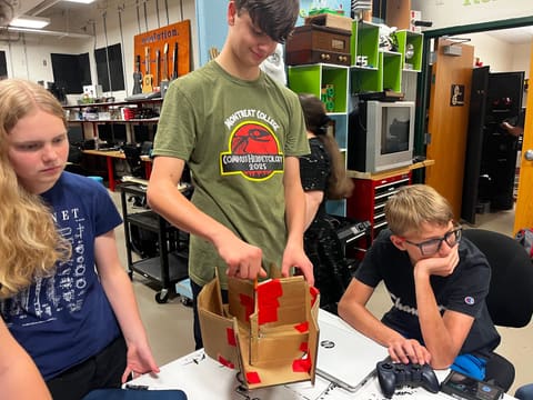 Students holding a cardboard drum prototype