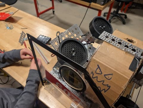 Prototype robot with a cardboard drum that has a face drawn on it